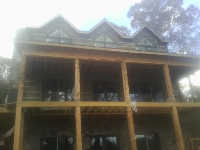 Dormers and porch framing on a large log home under construction — Roof Coating work by our crew in Flagler