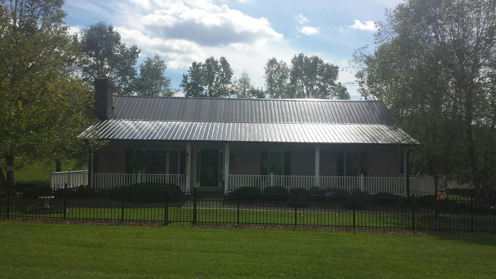 Gray metal roof on a brick ranch with a full width front porch — Gutter Guard Installation work by our crew in Flagler