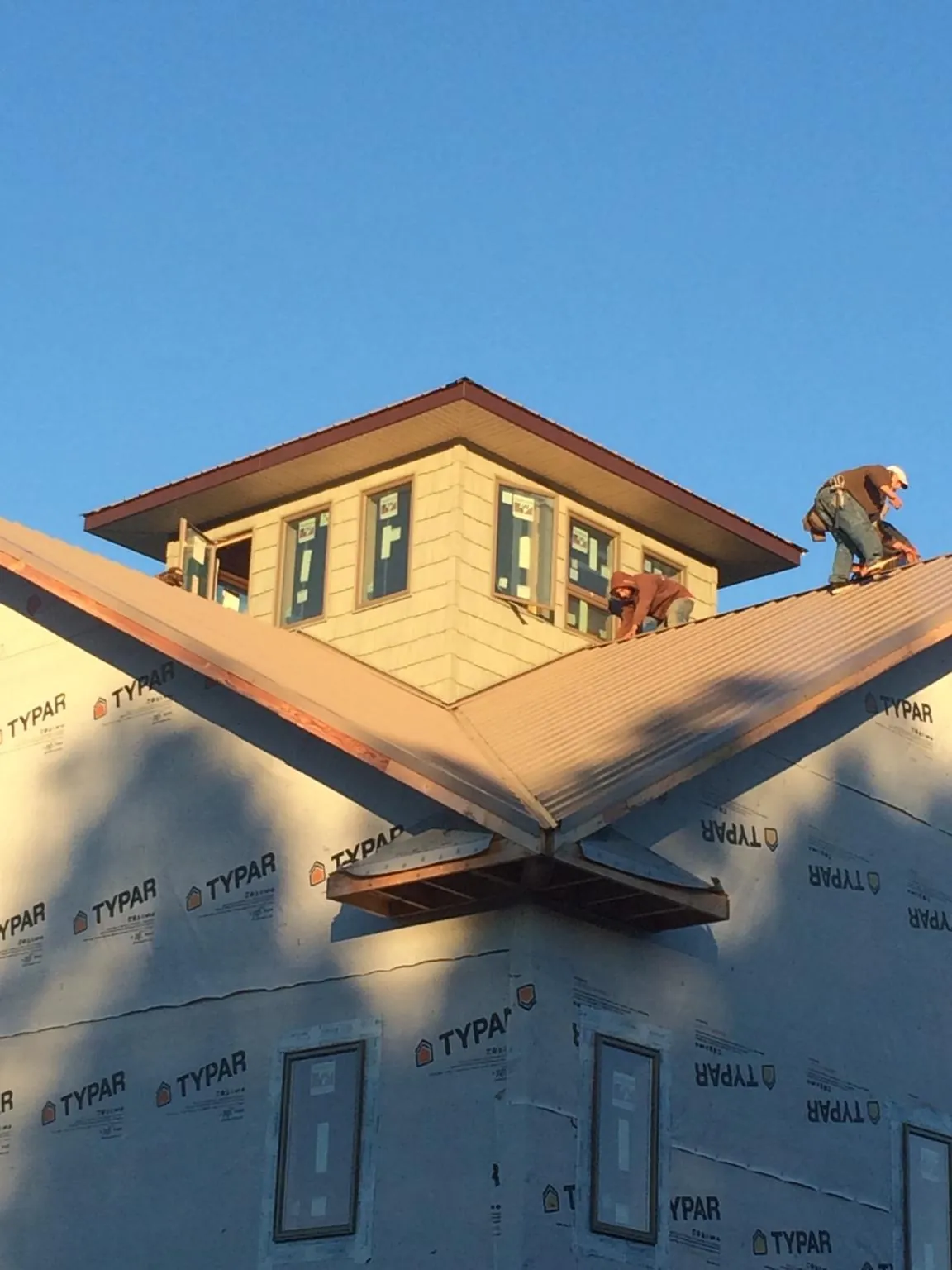 Roofers working around a rooftop cupola on a new metal roof at sunset — Roof Waterproofing in Flagler by Roofing Brothers